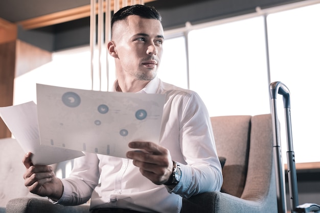 Working with documents. Close up of handsome prosperous man wearing hand watch working with documents