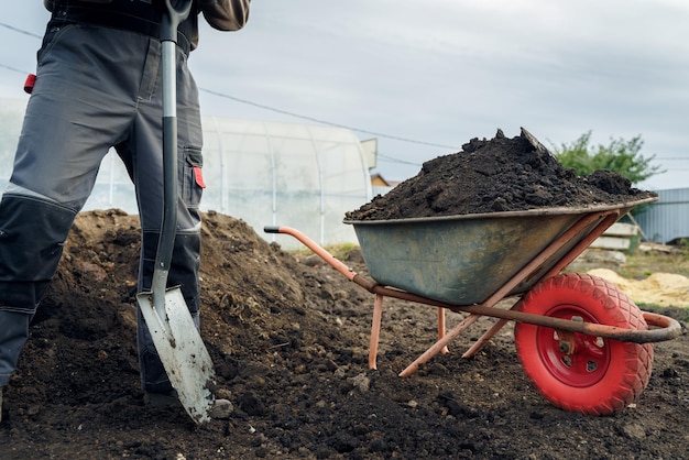 Working with garden tools, shovel and wheelbarrow on the site of a country house. Preparation for construction work.