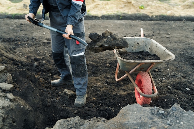 Working with garden tools shovel and wheelbarrow on the site of a country house preparation for