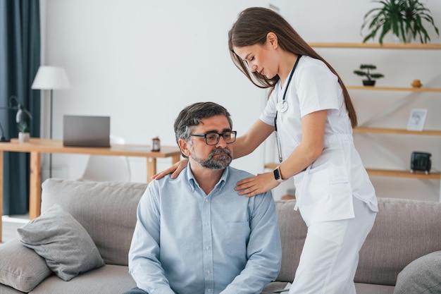 Working with mature man Professional nurse is in white coat is in the office