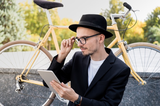 Working with technology out of office concept. Portrait of young man in casual suitusing a tablet computer in urban area