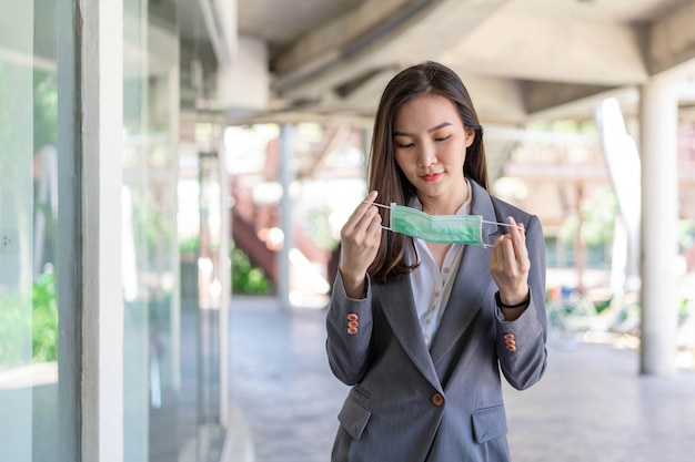 Concetto di donna lavoratrice una donna lavoratrice che si prepara prima di incontrare il cliente indossando la maschera usa e getta per proteggersi dal virus corona.