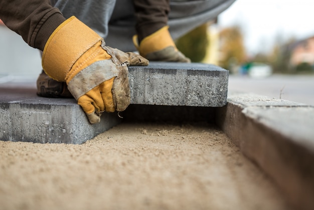 Photo workman laying exterior paving stones