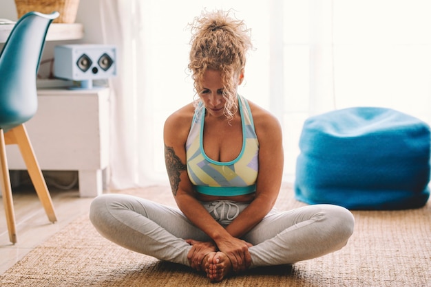 Workout fitness lifestyle at home young adult woman sitting on the carpet in balnce position like yoga or pilates. Adult female people rest and relax after active healthy sport session