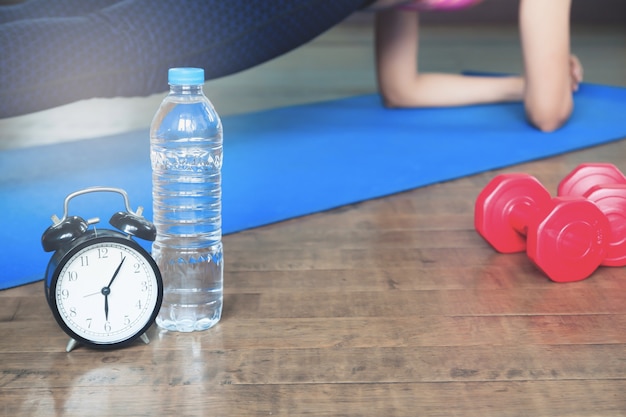 Allenamento e concetto di stile sano, sveglia, bottiglia d'acqua e attrezzature sportive, yoga a casa