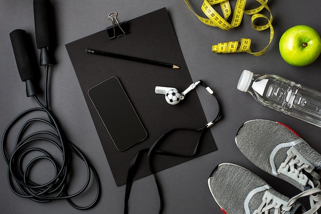 Workout plan with fitness food and equipment on gray background\
top view