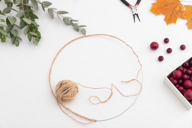 Workpiece of a wreath made of wire twine red beads and leaves Flat lay