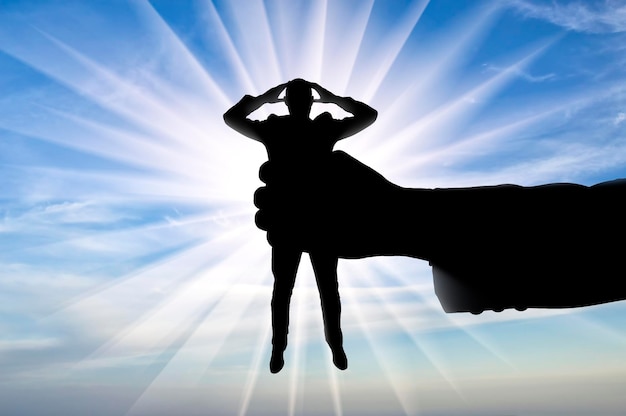 Workplace bullying concept. Silhouette of a manâs hand holds a man in a fist