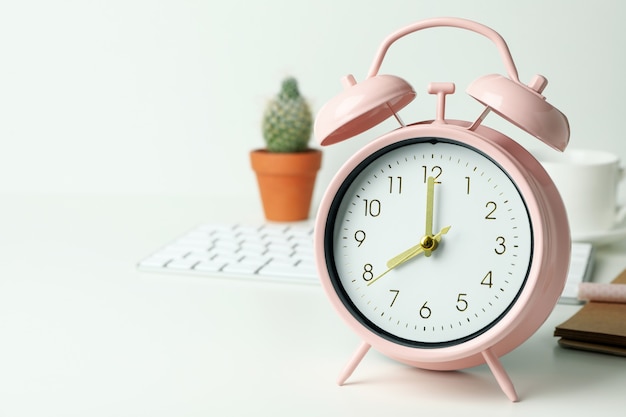 Workplace concept with alarm clock on white surface