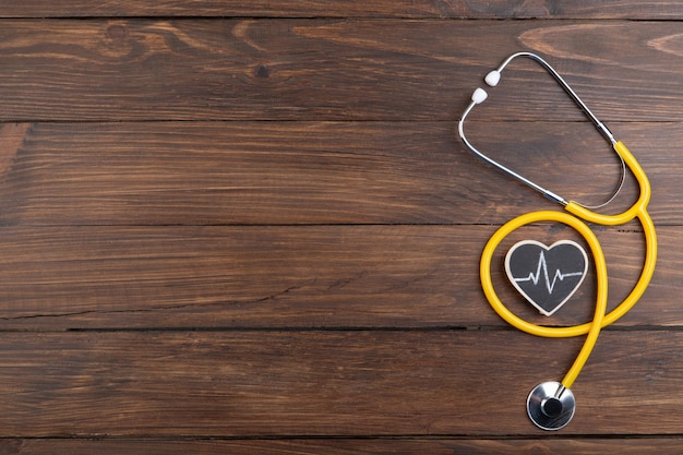 Workplace of a doctor Stethoscope and little heart on the wooden desk background