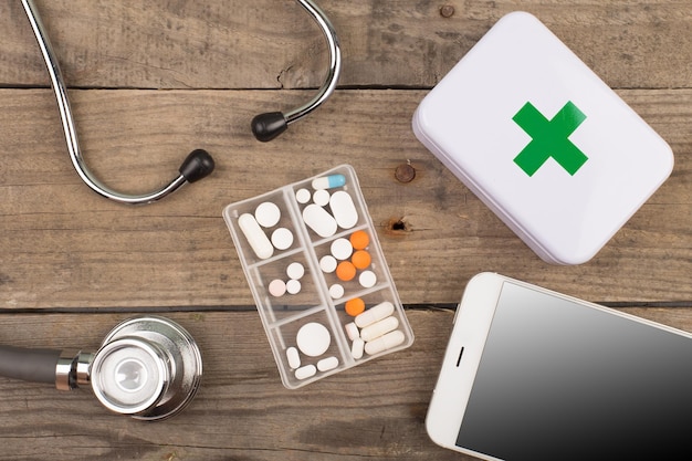 Workplace of a doctor Stethoscopeemergency kit and other stuff on wooden desk