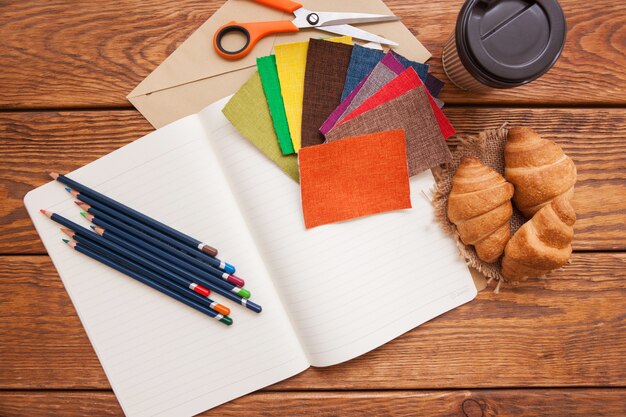 Luogo di lavoro dello stilista. matite, caffè e tessuti vista dall'alto. background creativo, scuola d'arte, ispirazione per il cucito e concetto di idea