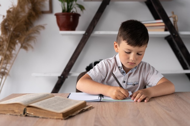 Workplace and homework of a schoolboy boy sitting at a lesson\
at a desk home school pupil or student preparing for tests or task\
handwritten text in a notebook or notepad back to school