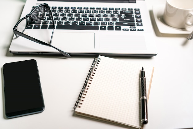 Workplace, laptop computer ,notebook and mobile phone on white table.business work concept.