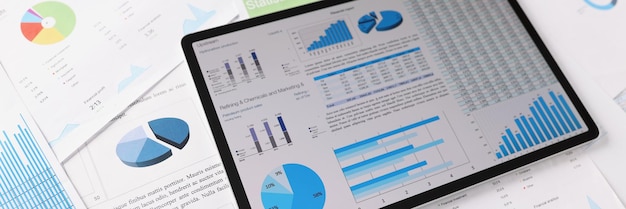 Photo workplace mess filled with with business papers tablet with diagrams and charts on device screen