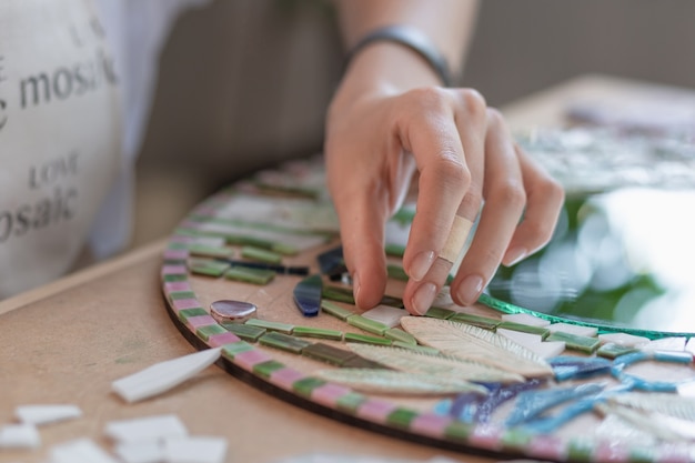 Workplace of the mosaic master womens hands holding tool for mosaic details in the process of making...