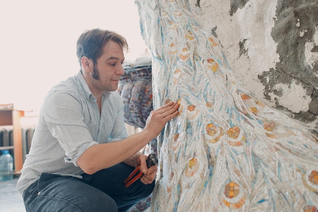 Maestri di mosaici per ambienti di lavoro che realizzano pannelli di mosaico in vetro smalto mosaicista uomo al lavoro