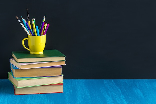 Workplace pupil Books Stationery on blue table on background bla