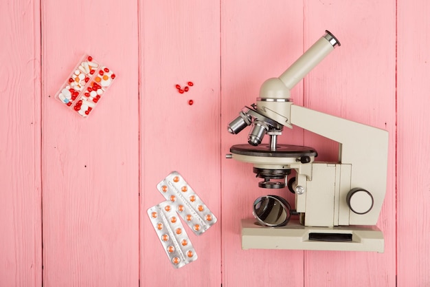 Workplace scientist doctor microscope pills on pink wooden table