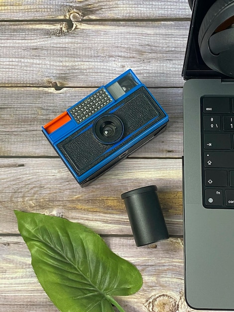 Workplace top view desktop with gadgets, laptop, camera and leaf