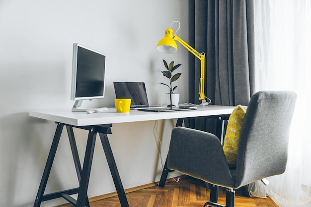 Workplace white desk with laptop and yellow cup designer working place