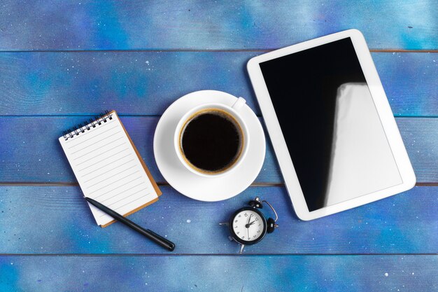 Workplace with blank digital tablet, paper on blue wooden work table. Above view 