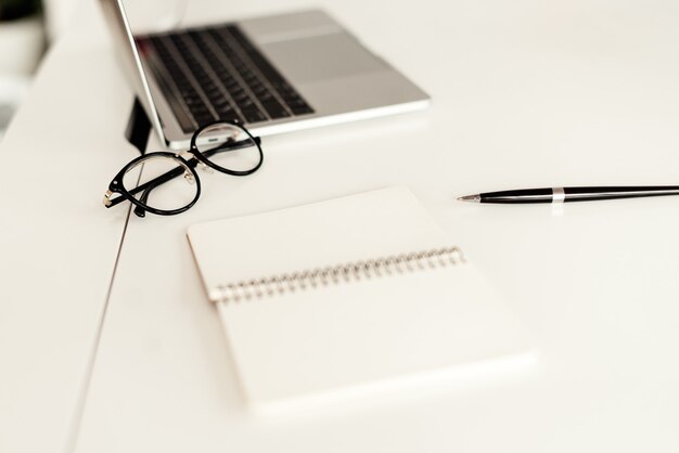 workplace with laptop, glasses and notebook on the desk in the office