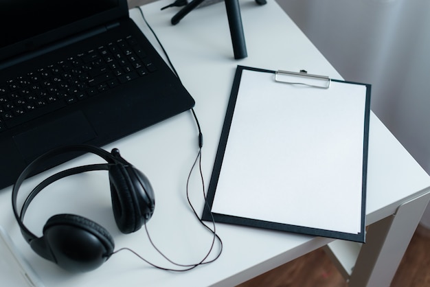 Workplace with laptop and headphones on a white desk