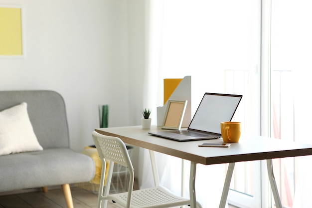 Photo workplace with modern laptop in the interior of the room