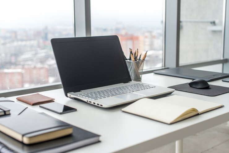 Photo workplace with notebook laptop comfortable work table in office windows and city view.