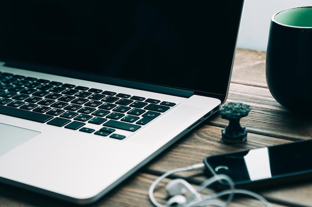 Workplace with open laptop on modern wooden desk angled notebook on table in home interior filtered image soft focus