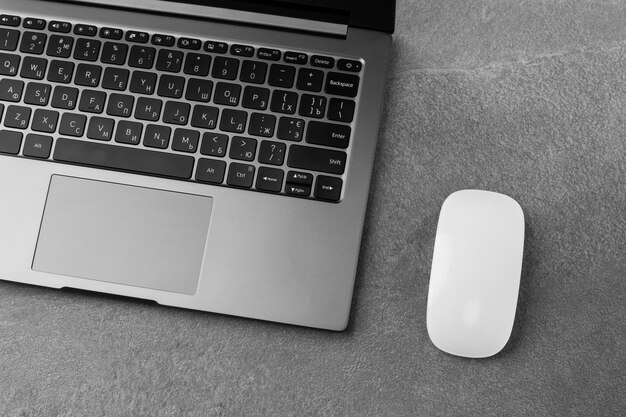 Workplace with open laptop with black screen and mouse on modern grey stone desk