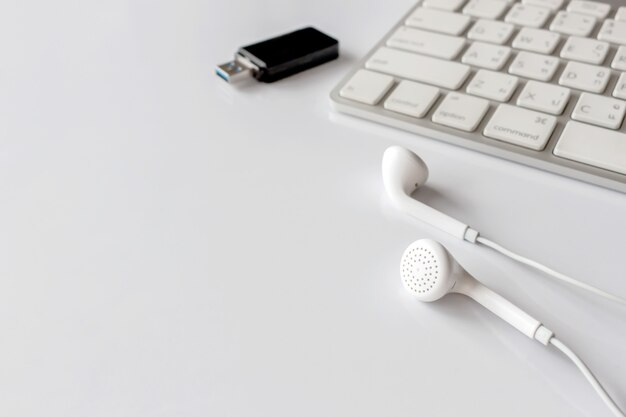 Photo workplace with text space, keyboard computer and earphone on wthte table. over light