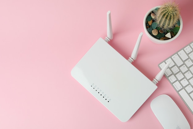 Workplace with Wi - fi router on pink background