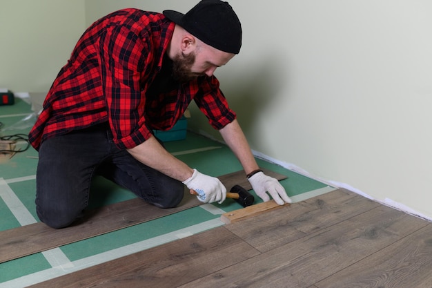 Works man installeert laminaatreparatie van het appartement met laminaatvloeren van hoge kwaliteit k-beeldmateriaal