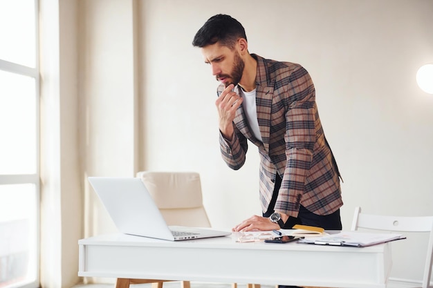 Works in the office Young stylish businessman in suit indoors Conception of success