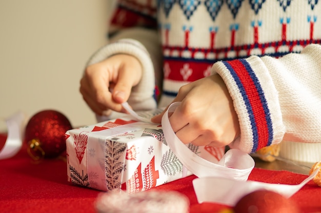 Workshop on packaging Christmas gifts. Women's hands tie a ribbon on a present box