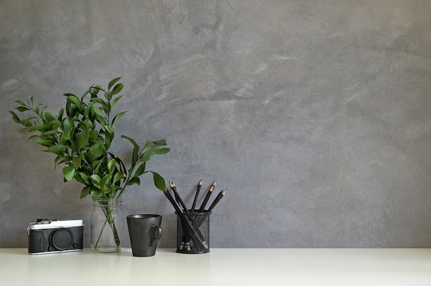 Photo workspace camera, coffee, pencil and plant decorate on white desk and loft wall.