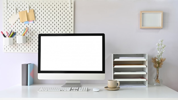 A workspace computer monitor is putting on a white working desk surrounded by office equipment.