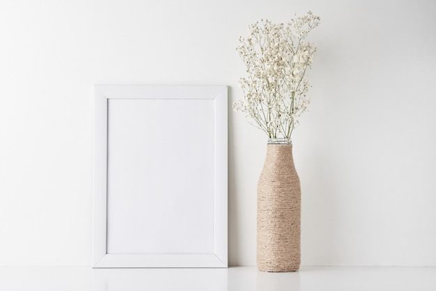 Workspace desk with empty frame and flower in vase