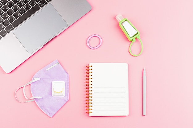 Workspace Desk With Laptop, Blank Notebook, Medical Mask on pink