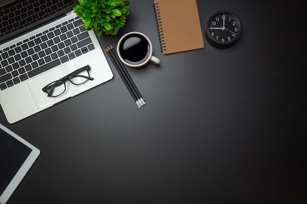 Workspace flat top view with a coffee cup and notebook on the
black desk surfaceoffice desk concept