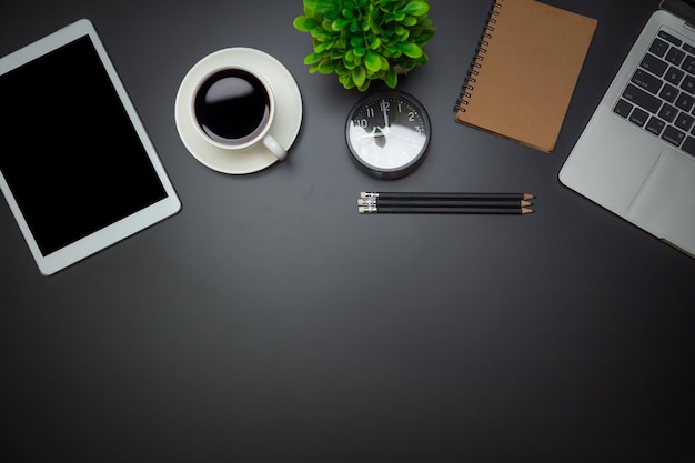 Workspace flat top view with a coffee cup and notebook on the\
black desk surfaceoffice desk concept