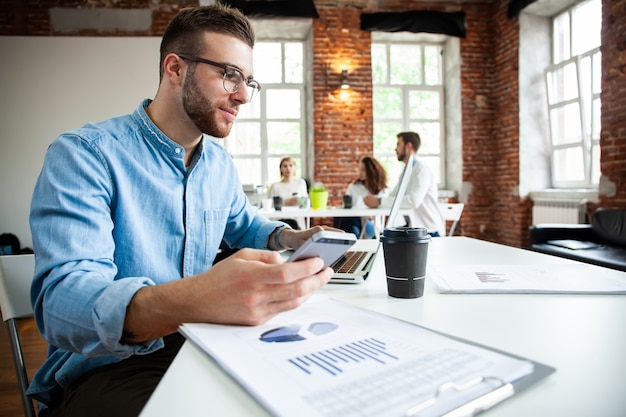 Workspace lifestyle concept. Businessman using smartphone. Handsome businessman is using a smartphone and smiling while working in office