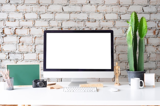 Workspace Mockup Computer with coffee mug, jar of pencil and notepad on white table 