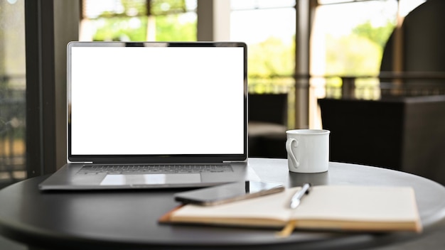 Рабочее пространство в современном кафе или коворкинг с макетом белого экрана ноутбука