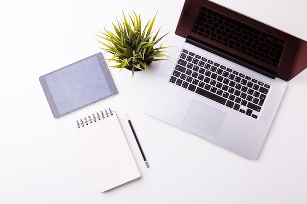 Workspace in office white desk with notebook tablet blank notebook and green flower