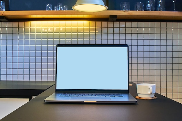 현대 로프트 인테리어에 빈 흰색 화면이있는 노트북에서 원격 온라인 작업을위한 작업 공간
