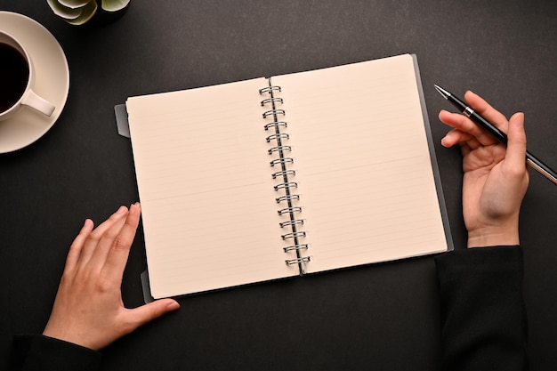 Workspace top view flat lay with a female writing something on her spiral notebook