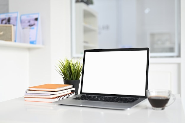 Photo workspace with a blank screen laptop and coffee cup on white table